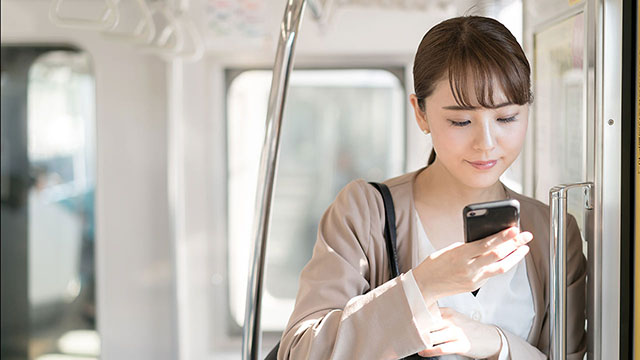 女性が移動中にスマホを操作しているイメージ